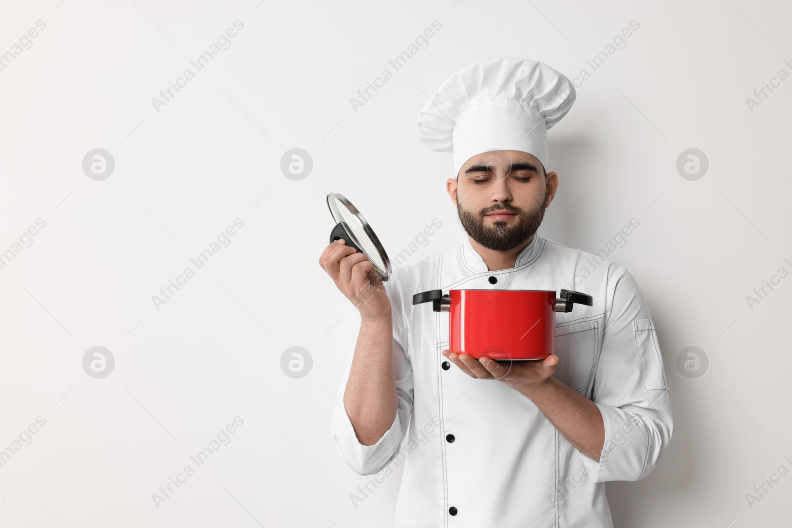 Photo of Professional chef with cooking pot on white background