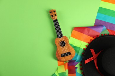 Photo of Black Flamenco hat and ukulele on green background, top view. Space for text