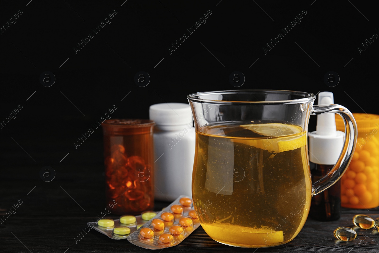 Photo of Composition with cold remedies on black wooden table. Sore throat treatment