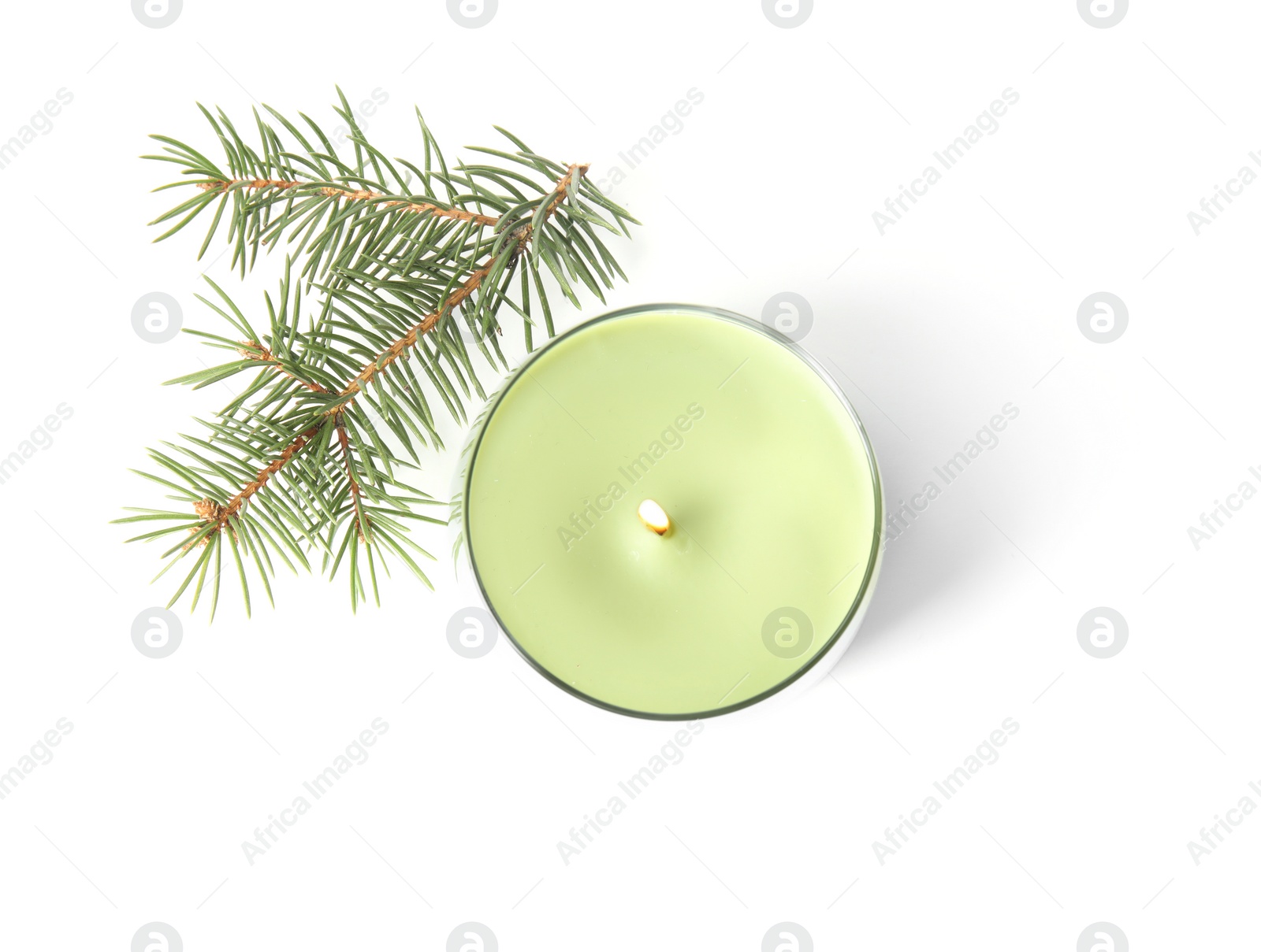 Photo of Green wax candle in glass holder and fir branch on white background, top view