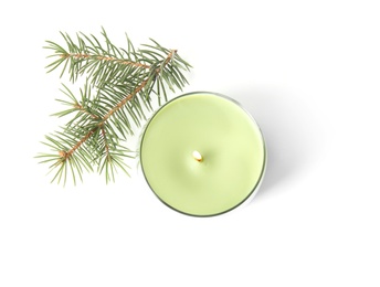 Green wax candle in glass holder and fir branch on white background, top view