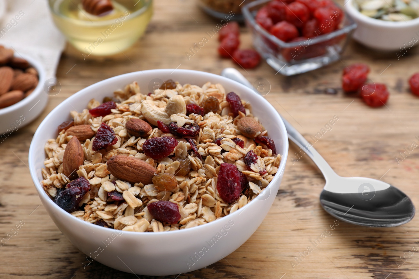 Photo of Tasty granola served with nuts and dry fruits on wooden table, closeup