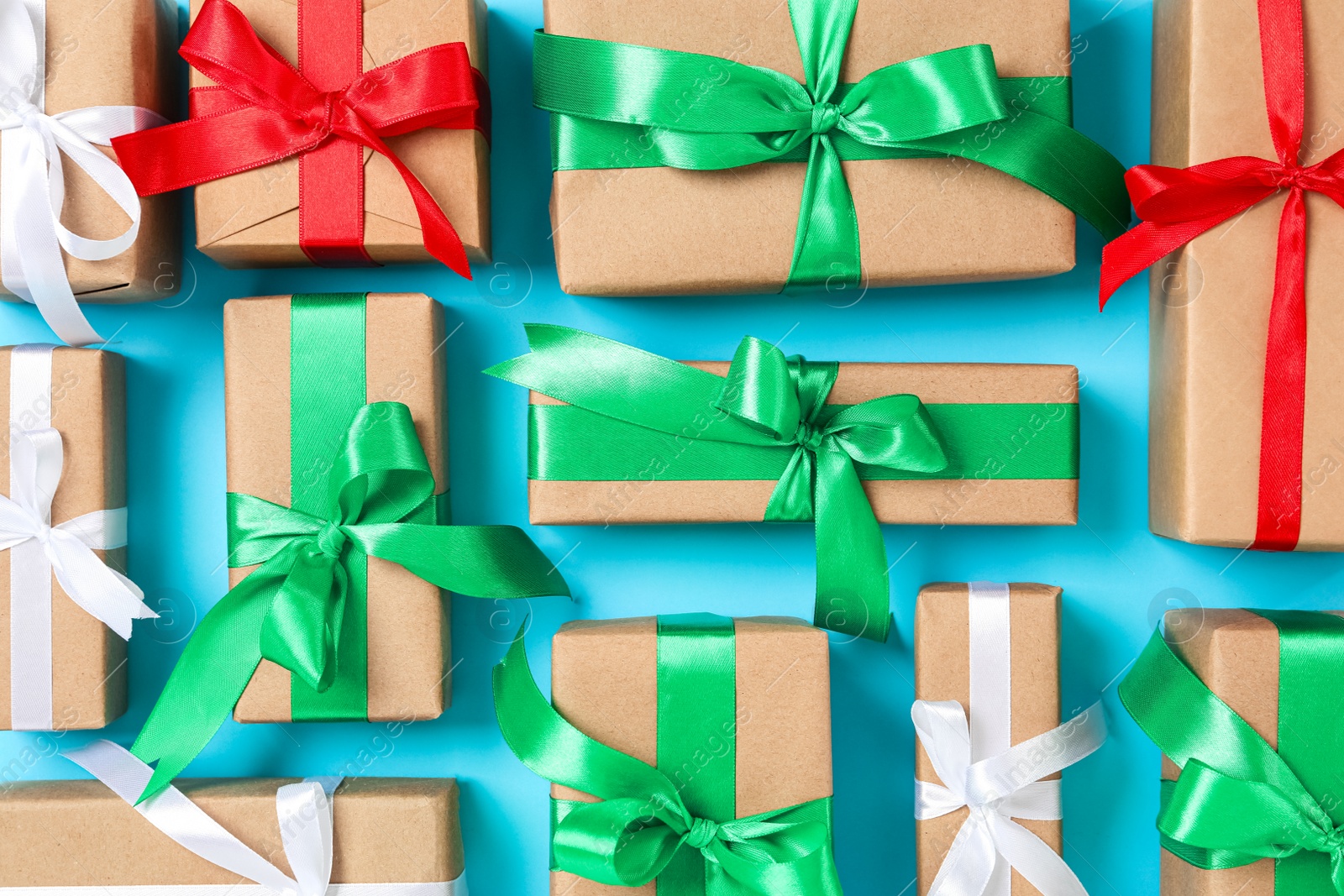 Photo of Christmas gift boxes with bows on light blue background, flat lay