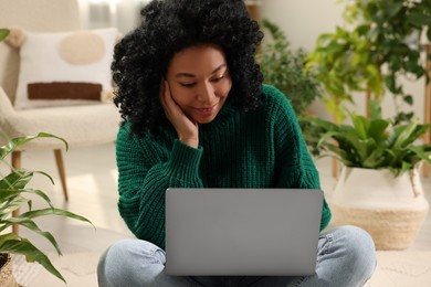 Relaxing atmosphere. Woman with laptop near potted houseplants at home