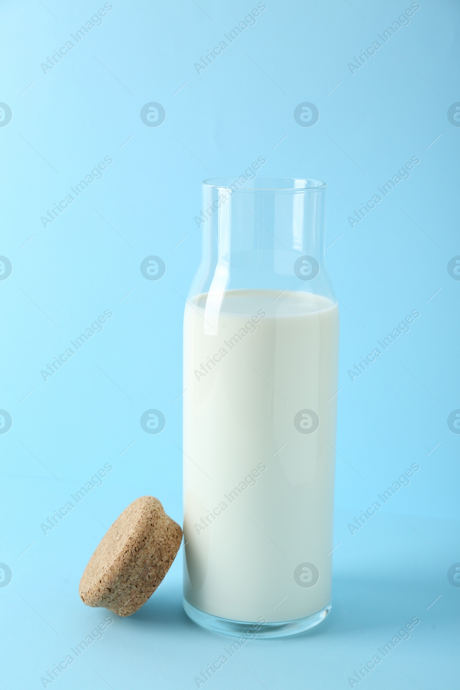 Photo of Glass carafe of fresh milk and lid on light blue background