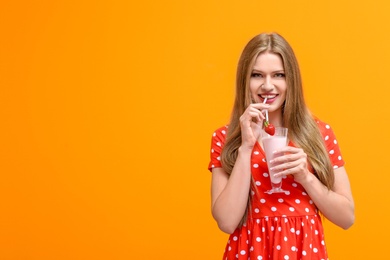 Photo of Young woman with glass of delicious milk shake on color background