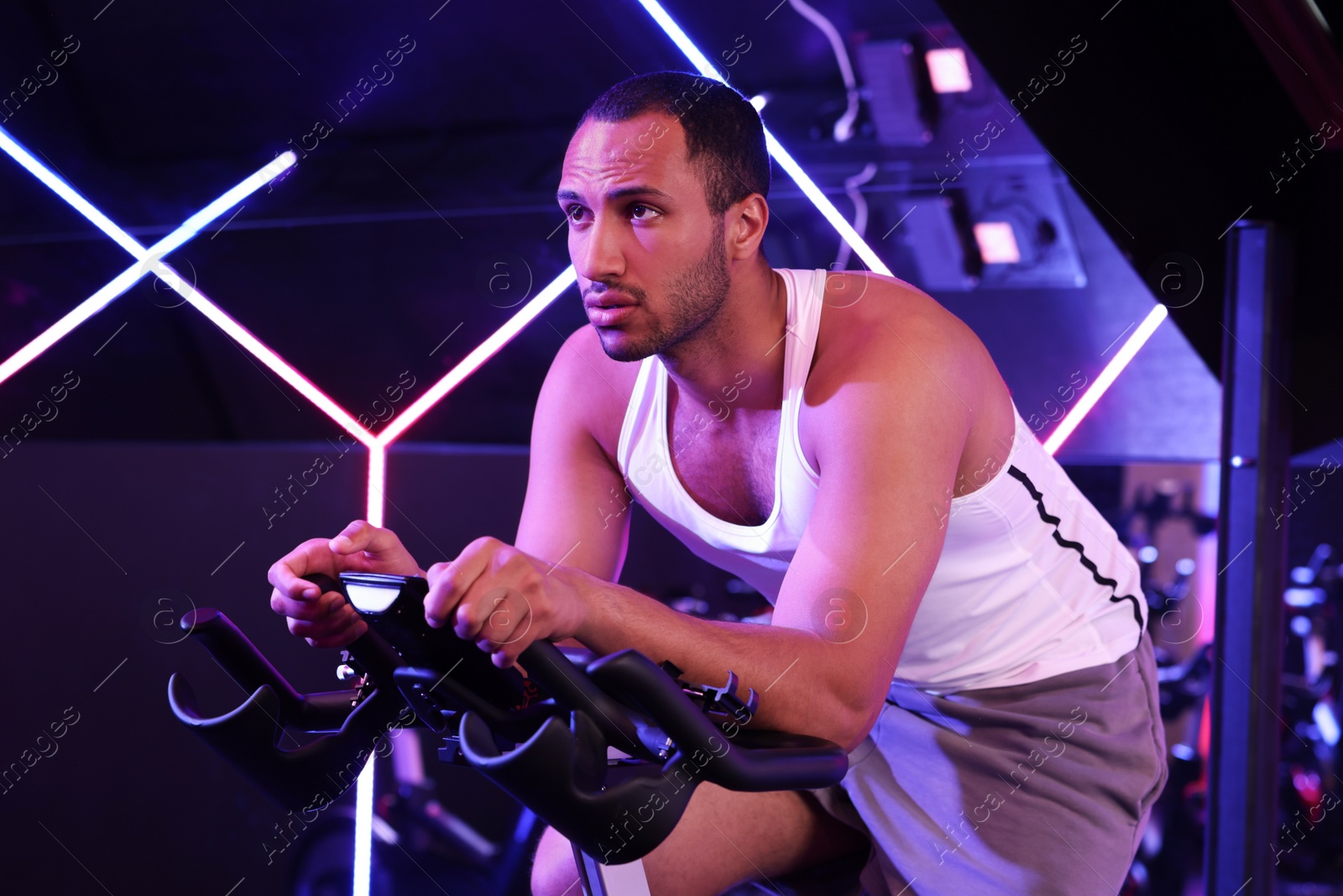 Photo of Young man training on exercise bike in fitness club