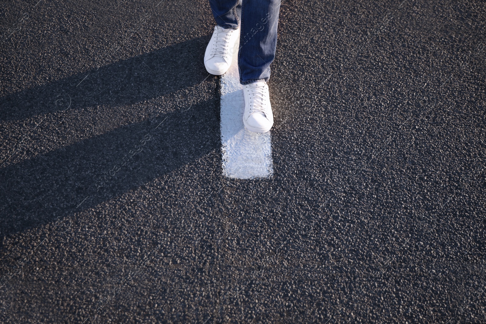 Photo of Man walking along white line on road, closeup with space for text. Way concept