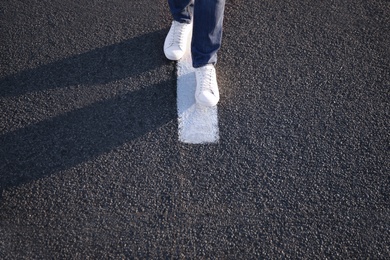 Photo of Man walking along white line on road, closeup with space for text. Way concept