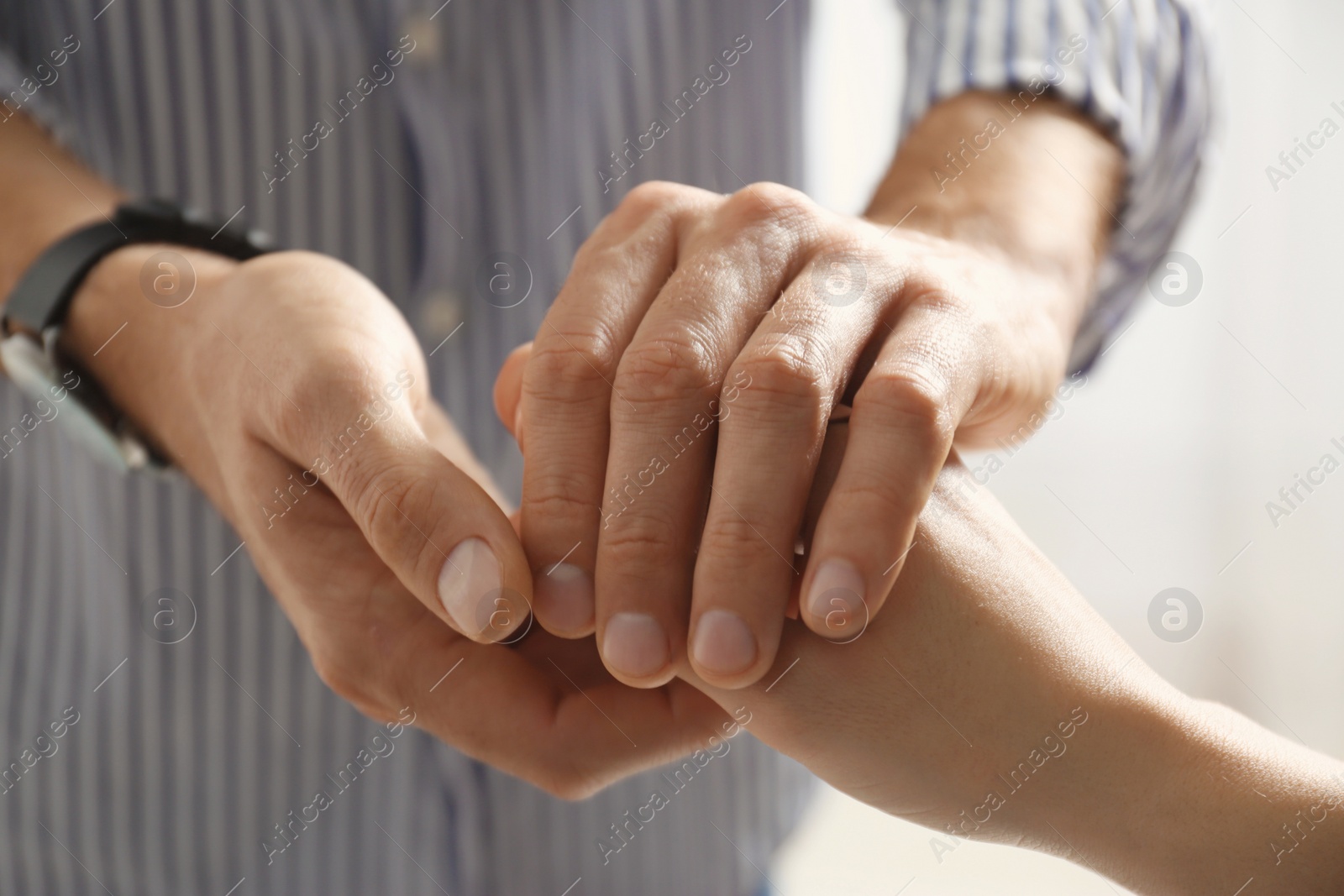 Photo of Man comforting woman on light background, closeup of hands. Help and support concept