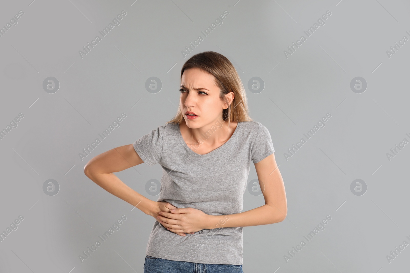 Photo of Young woman suffering from liver pain on grey background