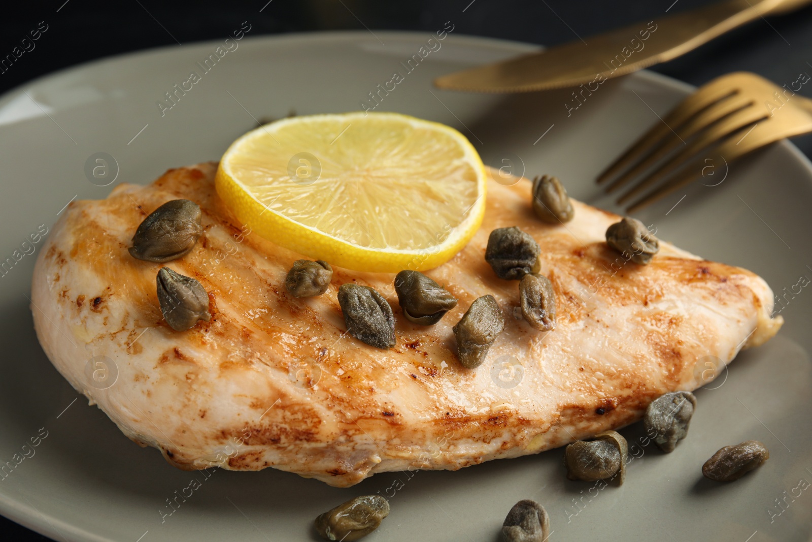 Photo of Delicious chicken fillet with capers and lemon on plate, closeup