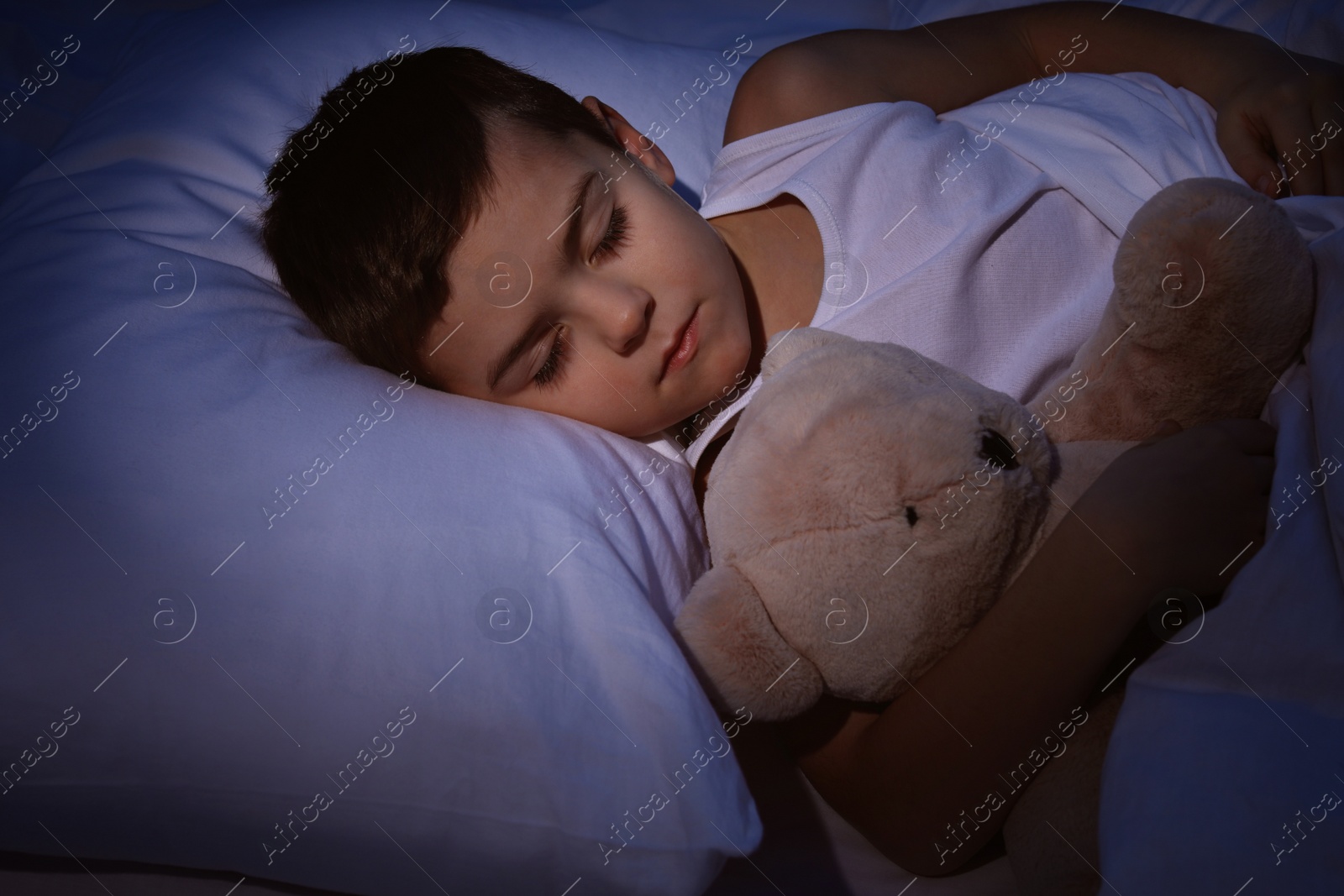 Photo of Little boy sleeping with teddy bear at home. Bedtime