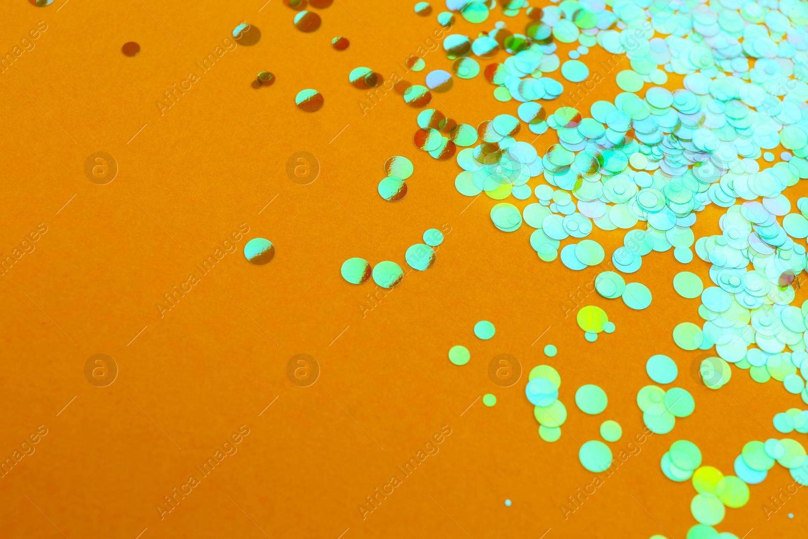 Photo of Shiny bright glitter on orange background. Space for text