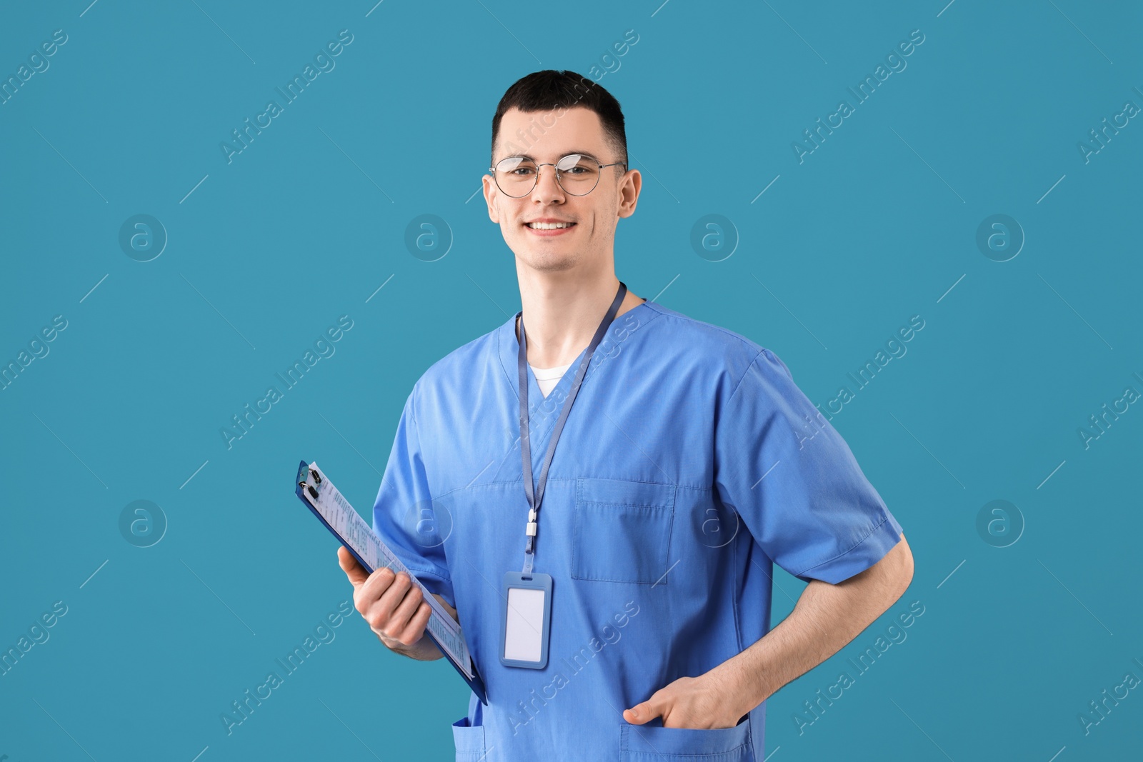 Photo of Portrait of smiling medical assistant with clipboard on light blue background