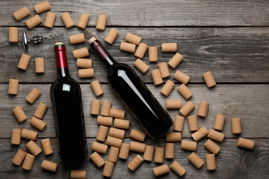 Photo of Wine corks, bottles and corkscrew on wooden table, flat lay