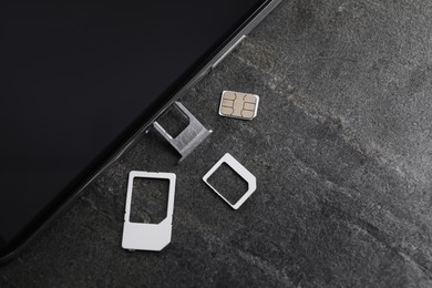 Photo of SIM card and mobile phone on grey table, flat lay
