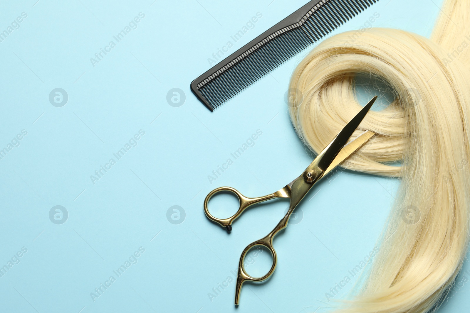 Photo of Professional hairdresser scissors and comb with blonde hair strand on light blue background, flat lay. Space for text