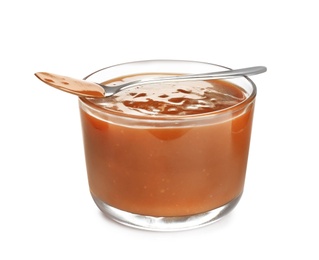 Photo of Glass and spoon of tasty caramel sauce isolated on white