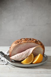 Photo of Delicious baked ham and orange slices on white wooden table. Space for text