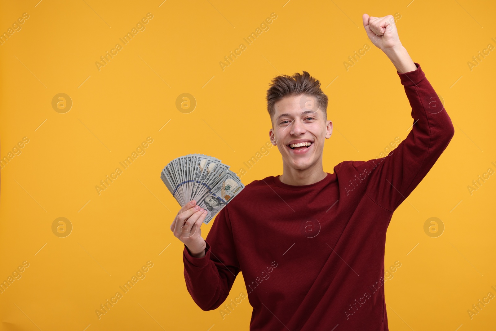 Photo of Happy man with dollar banknotes on yellow background. Space for text