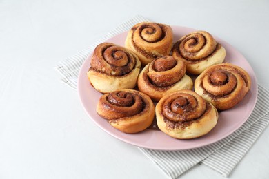 Photo of Many tasty cinnamon rolls on white table