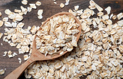 Photo of Spoon with oatmeal on wooden table, flat lay