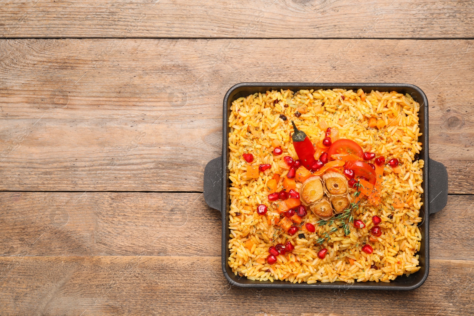 Photo of Tasty rice pilaf with vegetables on wooden table, top view. Space for text