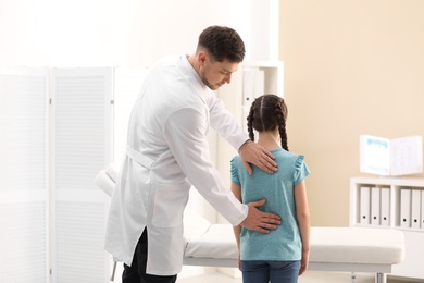 Chiropractor examining child with back pain in clinic