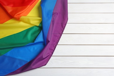 Bright rainbow gay flag on wooden background, top view with space for text. LGBT community