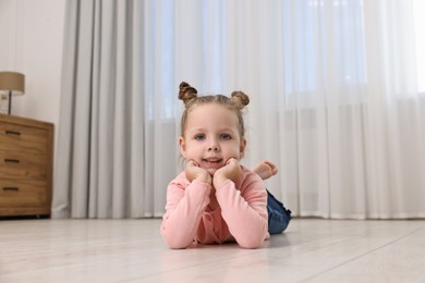 Photo of Cute little girl lying on warm floor at home. Heating system