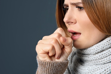 Photo of Woman suffering from cough on dark background, closeup. Space for text
