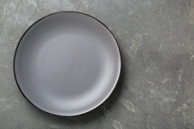 Photo of Empty ceramic plate on grey table, top view. Space for text