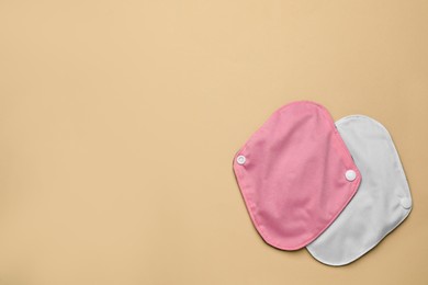 Reusable cloth menstrual pads on beige background, flat lay. Space for text