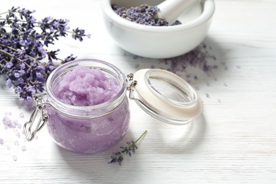 Natural sugar scrub and lavender flowers on white wooden table, space for text. Cosmetic product