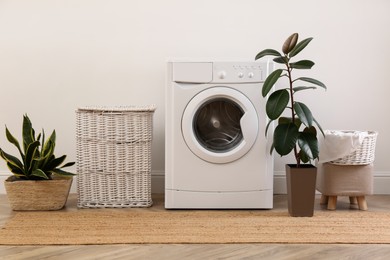 Photo of Laundry room interior with modern washing machine and wicker basket near white wall