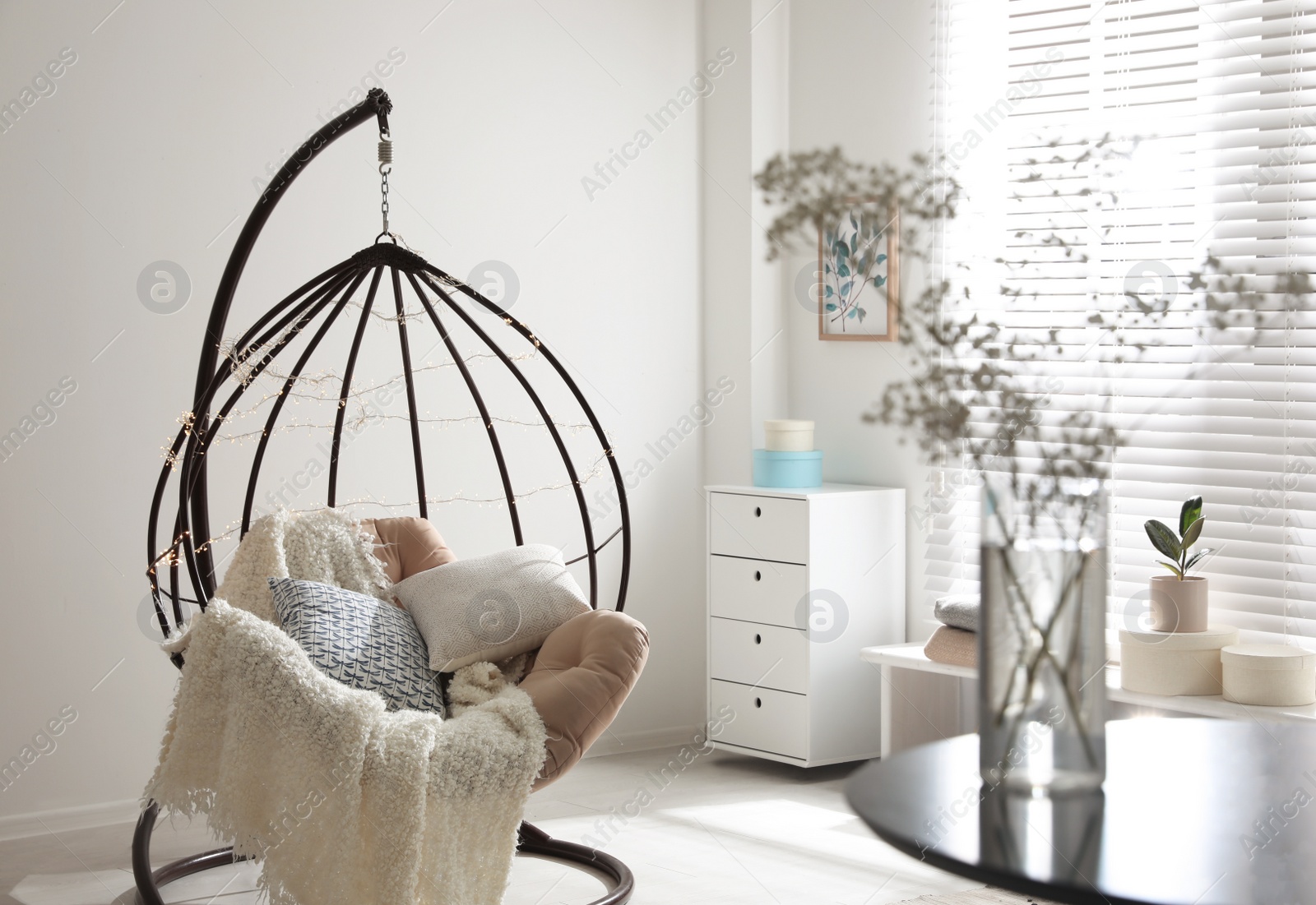 Photo of Cozy hanging chair with fairy lights in modern living room. Interior design