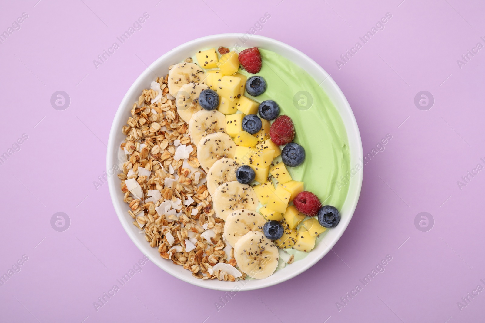 Photo of Tasty matcha smoothie bowl served with fresh fruits and oatmeal on violet background, top view. Healthy breakfast