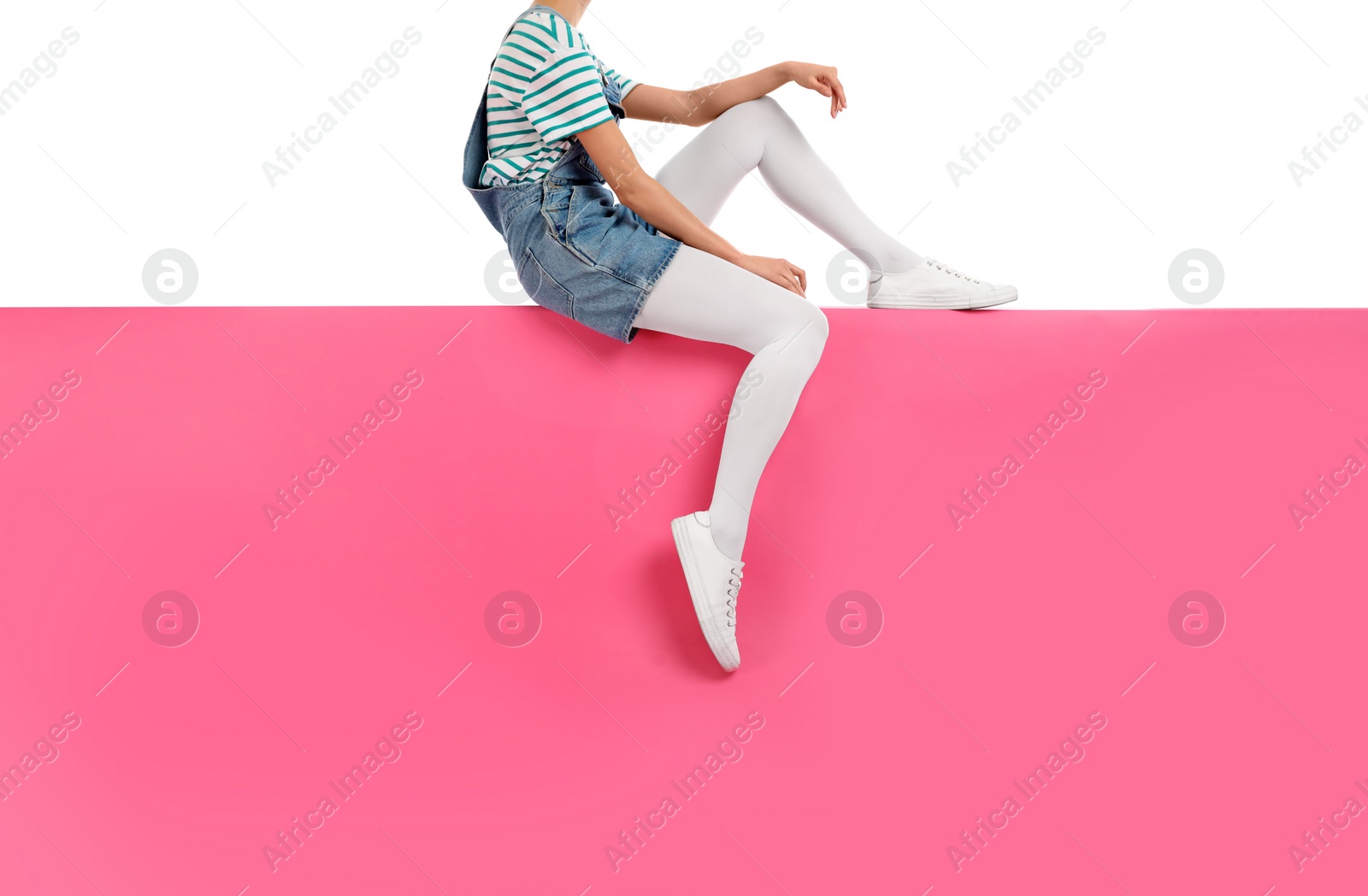 Photo of Woman wearing white tights and stylish shoes sitting on color background, closeup