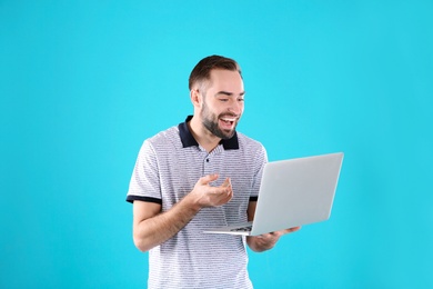 Photo of Man using laptop for video chat on color background