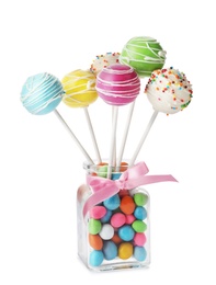 Delicious colorful cake pops in glass with candies on white background