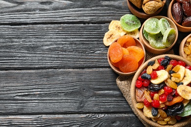 Photo of Bowls of different dried fruits on wooden background, top view with space for text. Healthy lifestyle