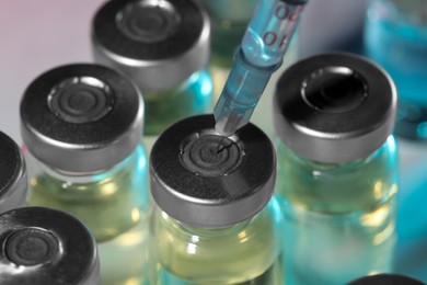 Photo of Filling syringe with medicine from vial on light background, closeup