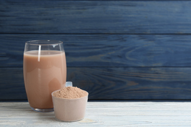 Protein shake and powder on white wooden table, space for text