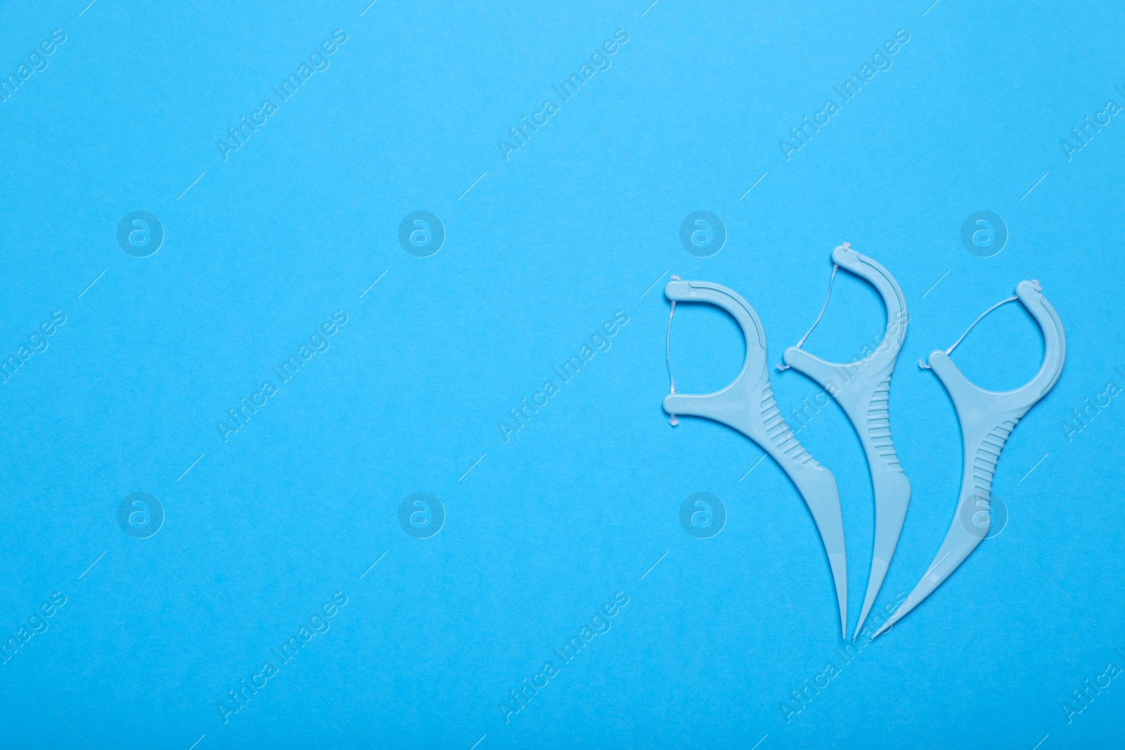 Photo of Dental flossers on light blue background, flat lay. Space for text