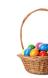 Decorated Easter eggs in wicker basket on white background