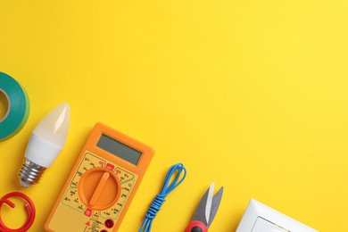 Photo of Flat lay composition with electrician's tools and accessories on yellow background, space for text