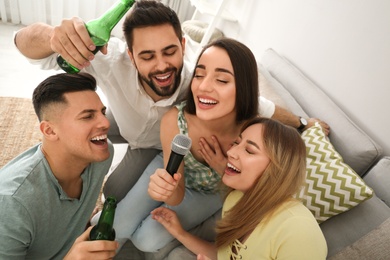 Happy friends singing karaoke together at home