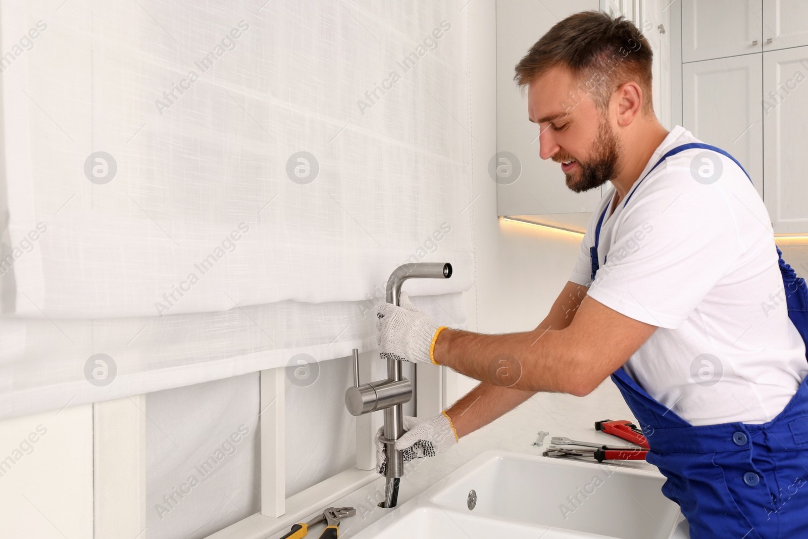 Photo of Professional plumber repairing water tap in kitchen