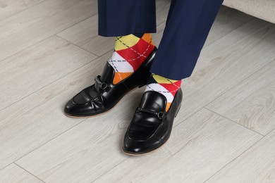 Photo of Man wearing stylish shoes and colorful socks indoors, closeup